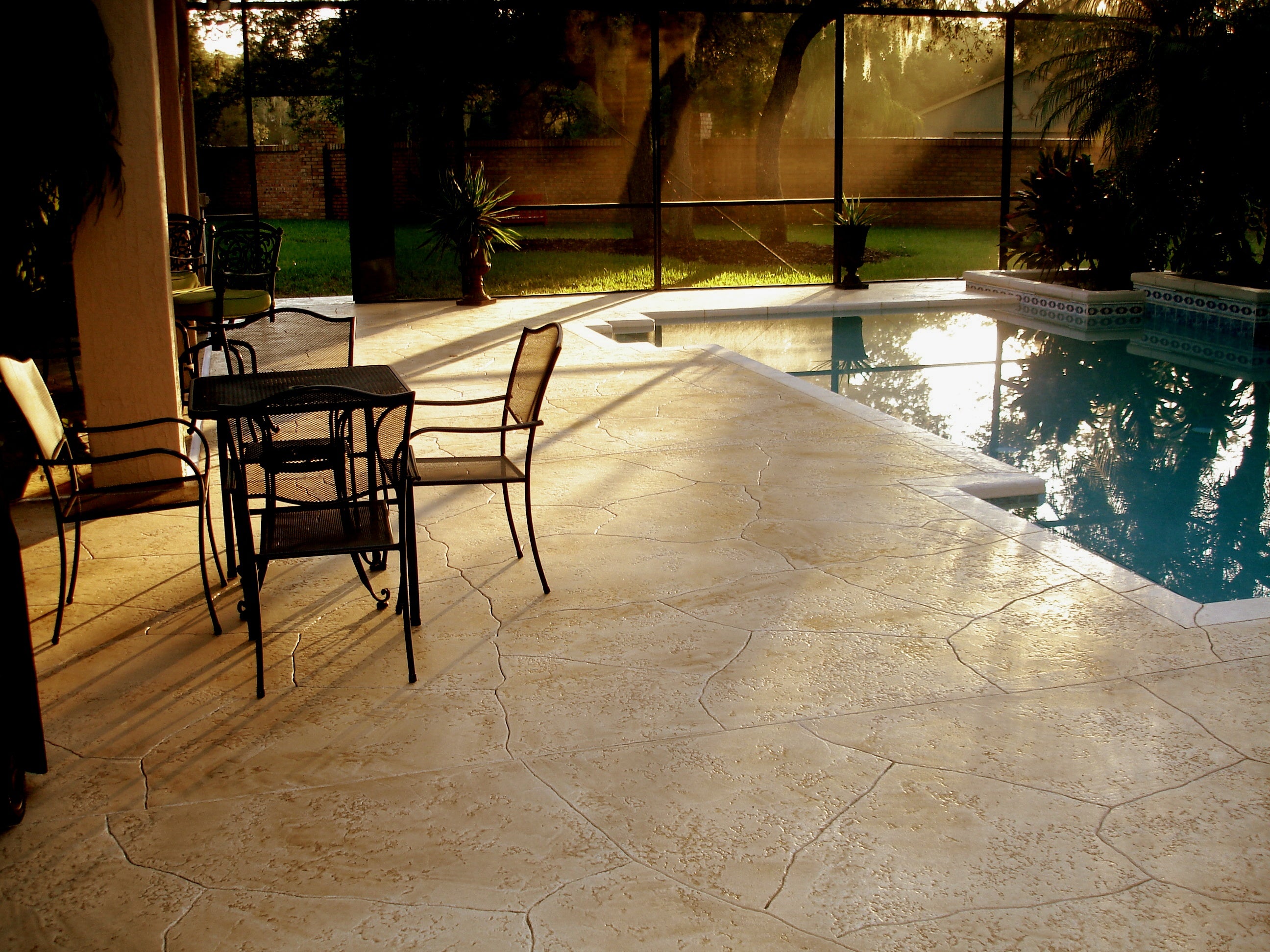 A table and chairs resting on an enclosed swimming pool deck