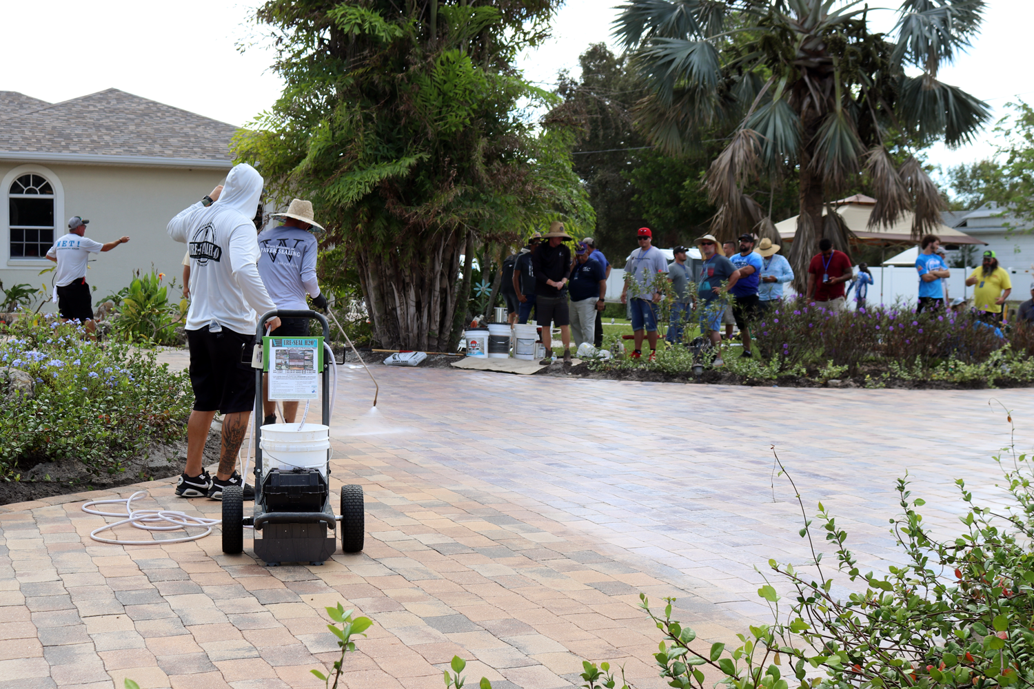 Men spraying ICT product onto a driveway made of concrete pavers